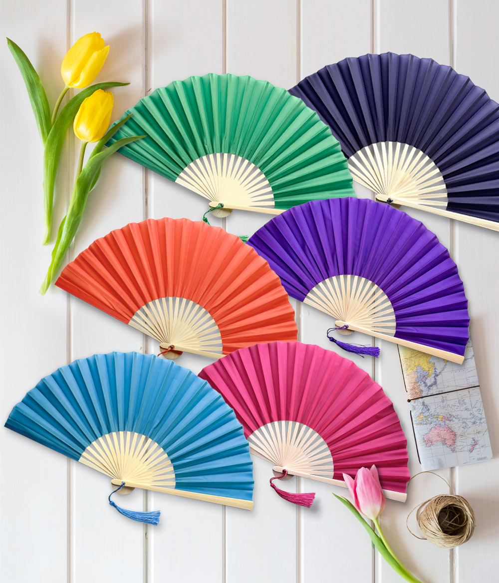 A collection of vibrant folding fans in various colors displayed on a wooden table.