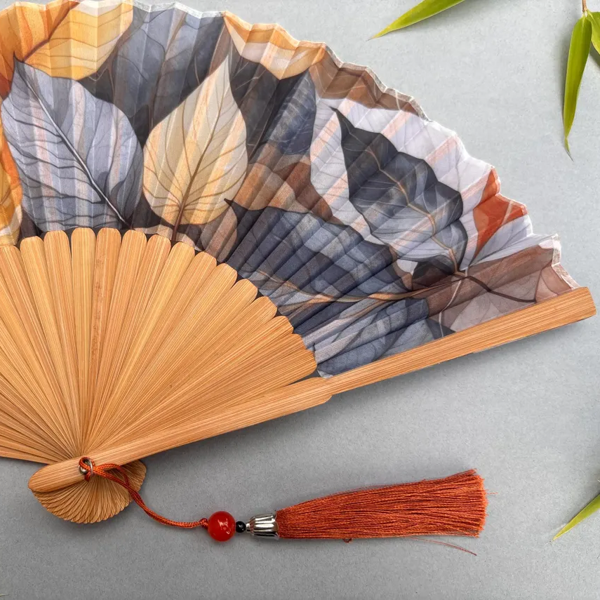 Handheld fan with leaf pattern on a gray background