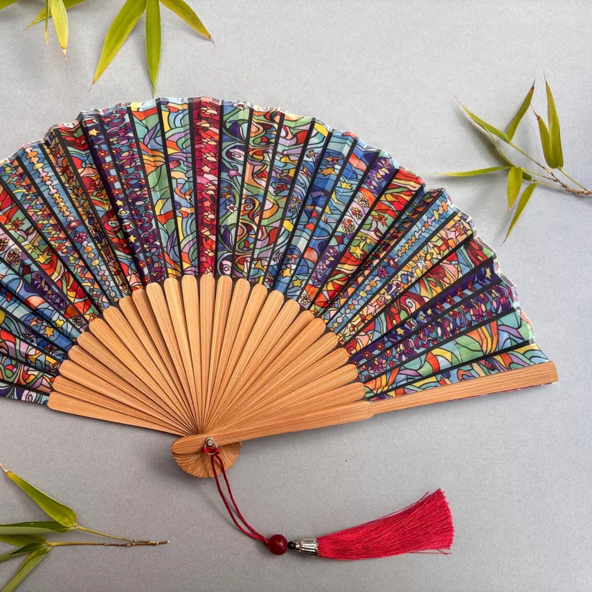 Colorful hand-fan with bamboo structure and decorative tassel on a light gray background
