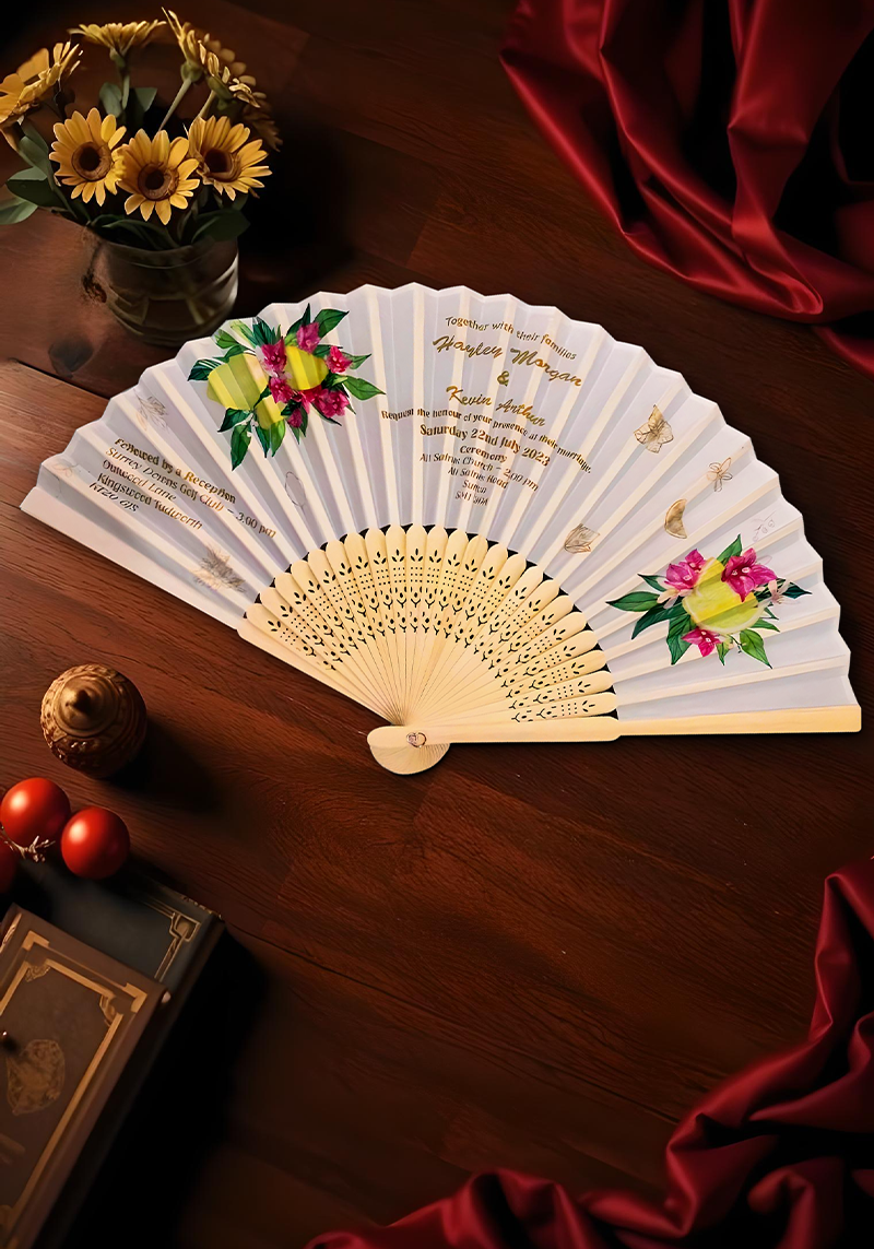 A table adorned with a book and a bouquet of flowers, accompanied by a decorative hand fan.