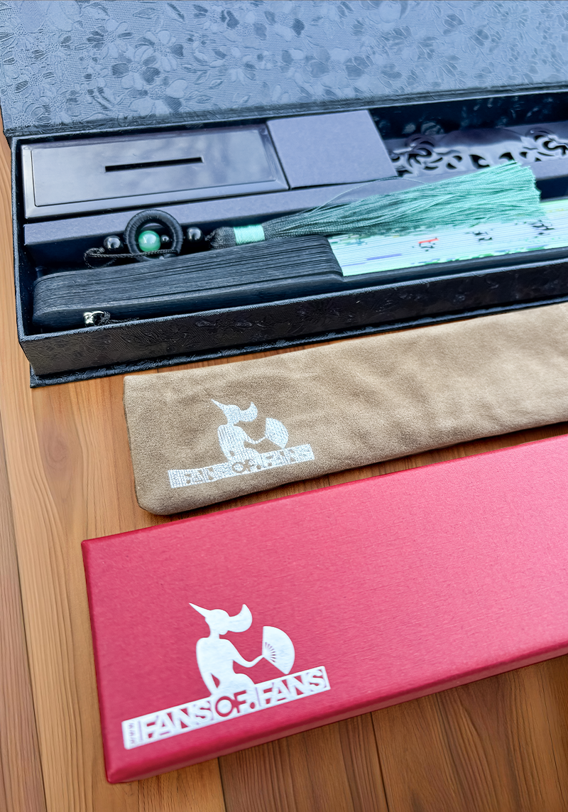 A foldable hand fan case in red and black placed on a wooden floor.