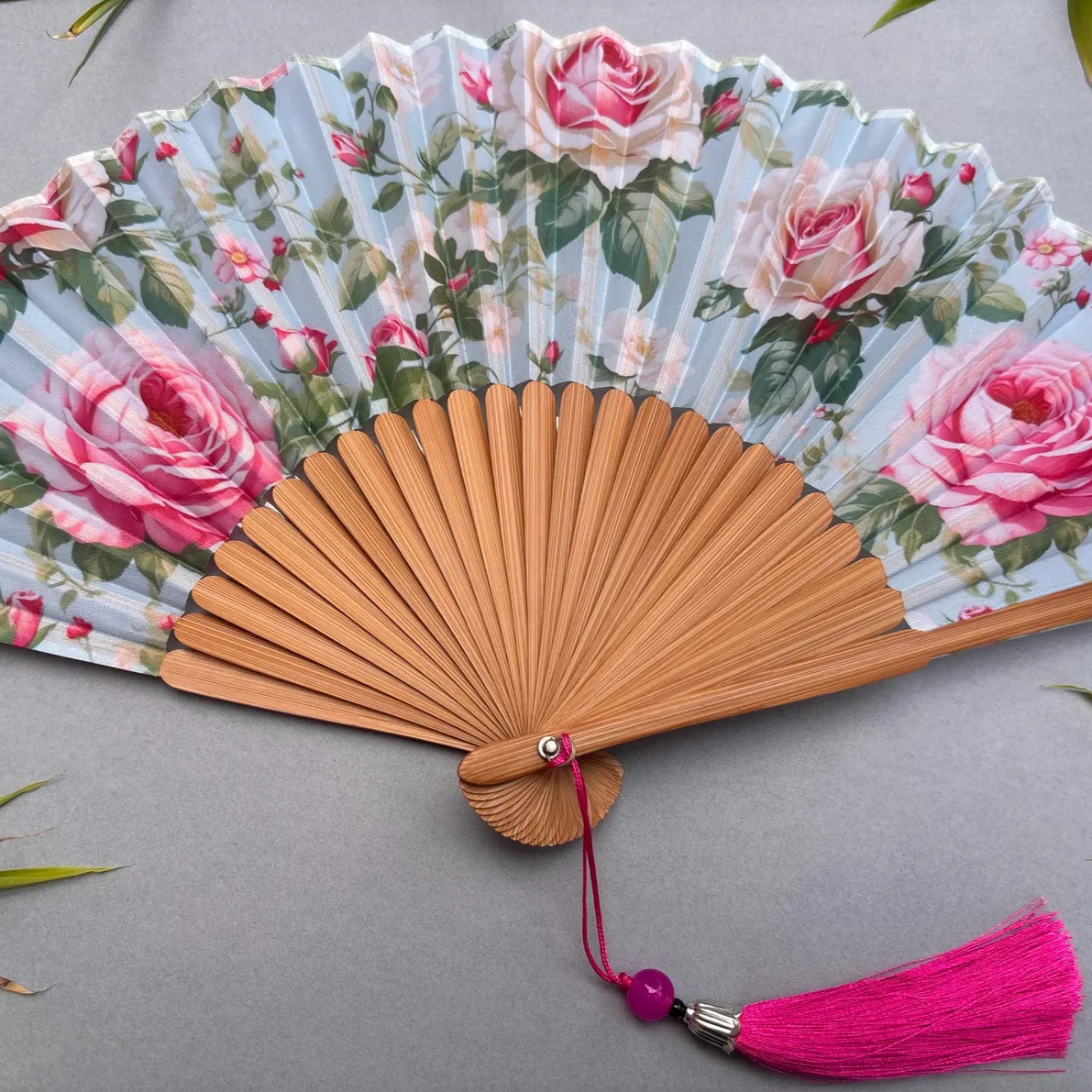 Floral-patterned hand fan with pink roses on a gray background