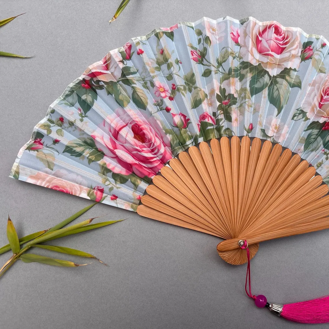 Floral-patterned hand fan with pink roses on a gray background