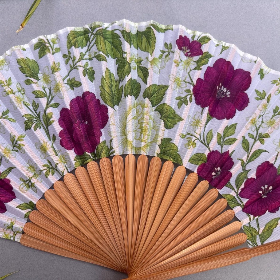 Floral-patterned hand fan on a gray background