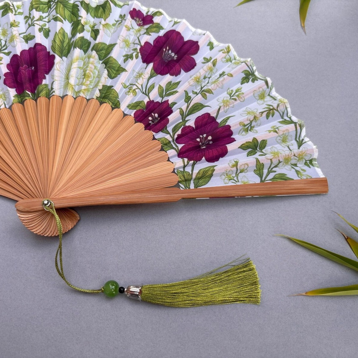 Floral-patterned hand fan on a gray background