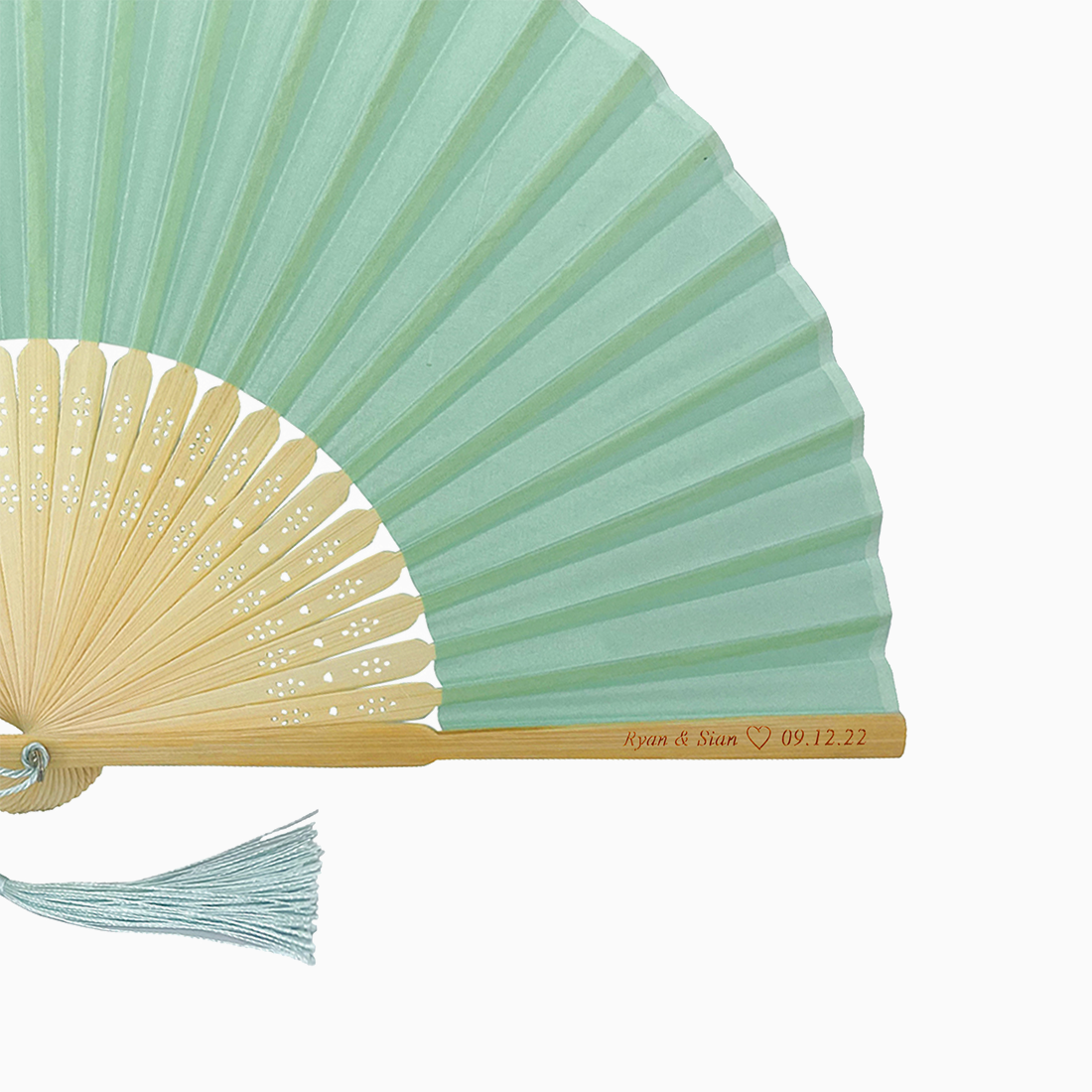 A folding fan with Light Turquoise and beige hues features a stylish tassel. Its engraved text on the wooden rib, radiating elegance and charm.