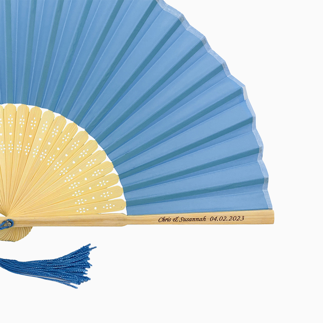 A folding fan with true blue and beige hues features a stylish tassel. Its engraved text on the wooden rib, radiating elegance and charm.