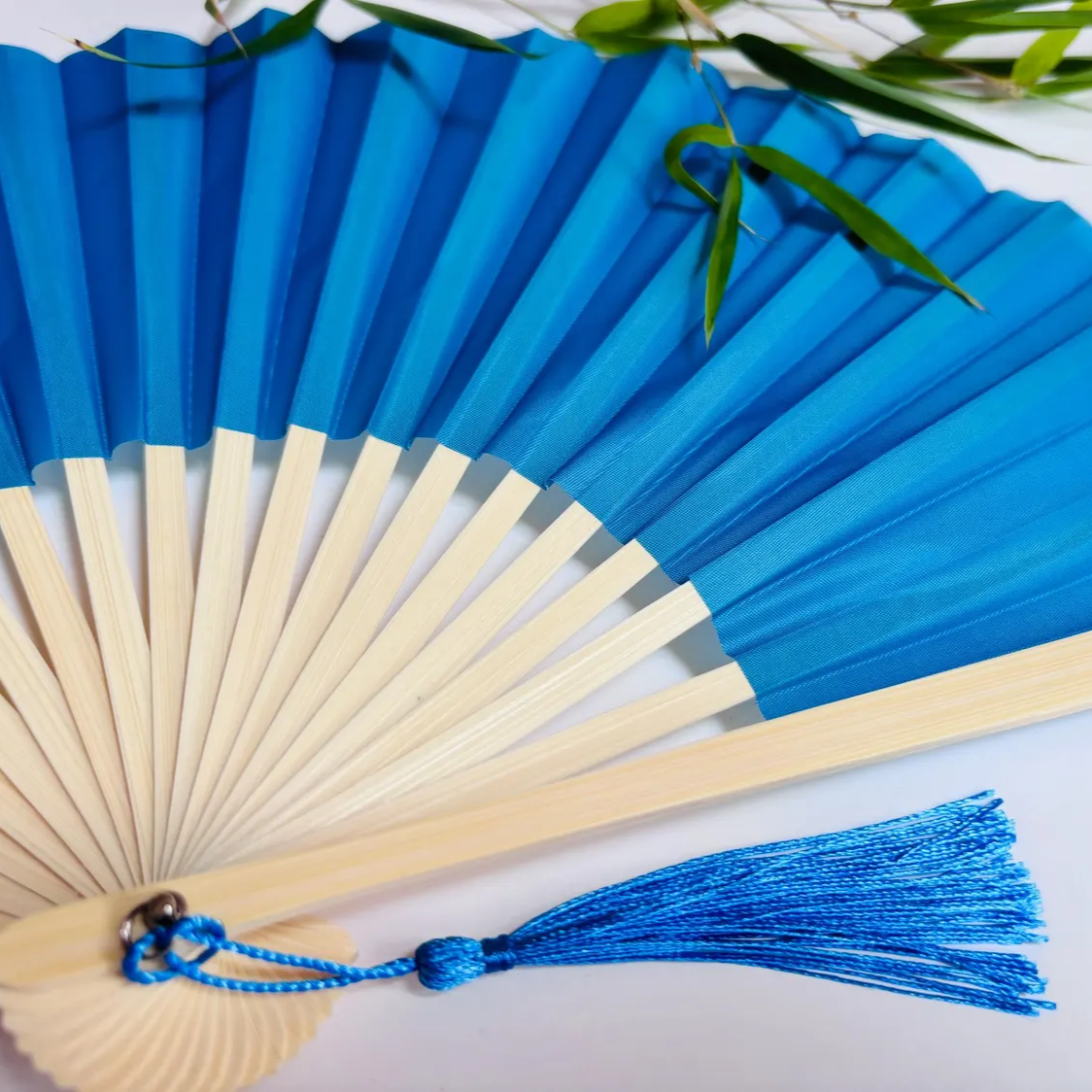 Baby Blue hand fan with a tassel on a white background