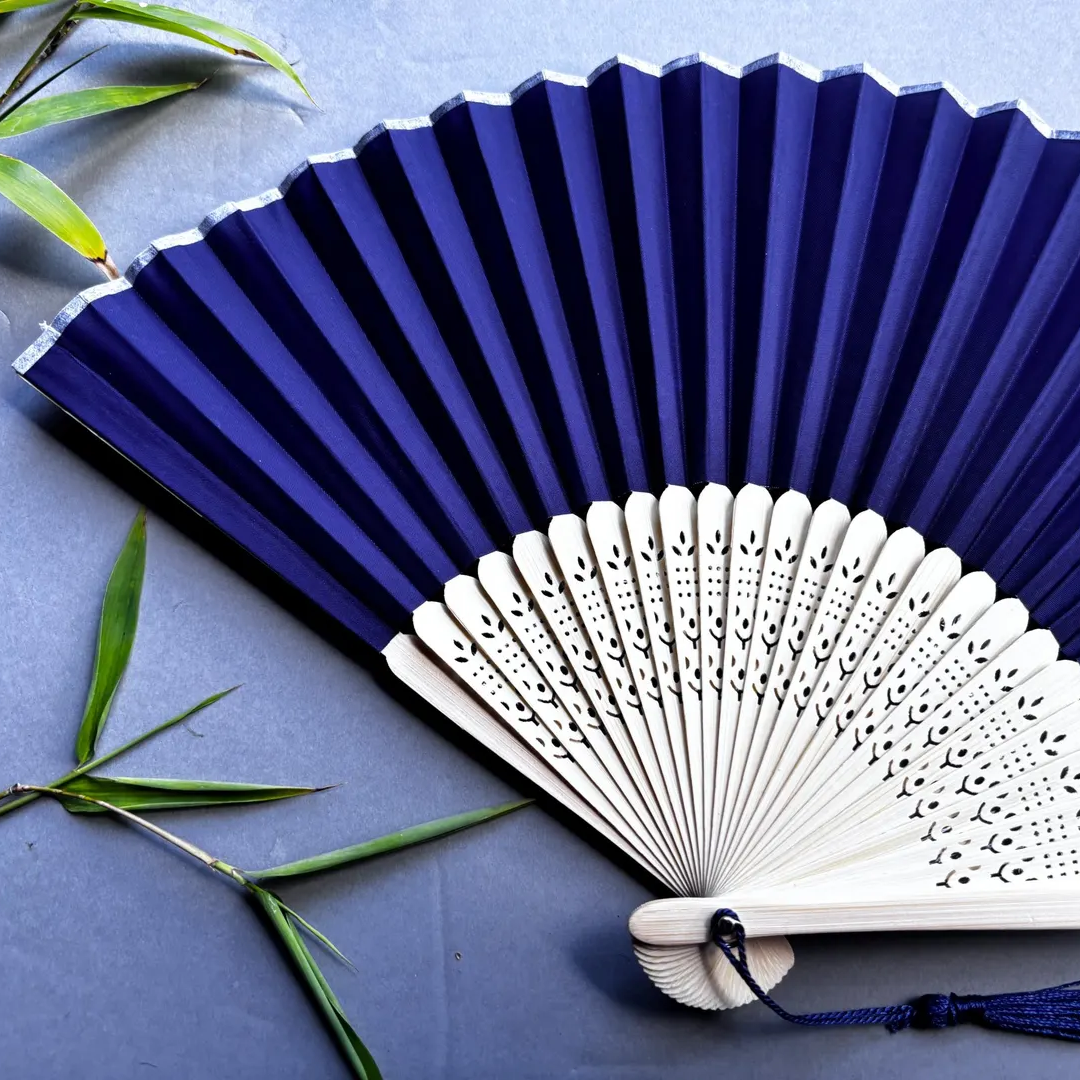 Two fans, one blue and one white with intricate patterns, on a gray background.