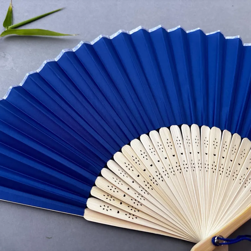 Blue folding fan with wooden handle on a gray background