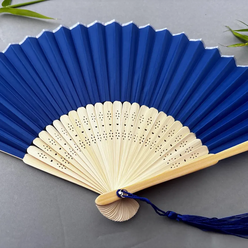 Blue and beige hand fan on a gray background