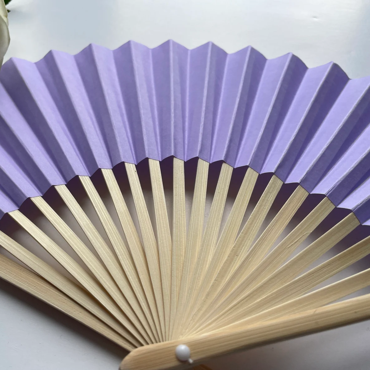A purple paper folding fan featuring a tassel, elegantly designed in a solid color.