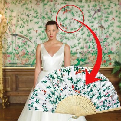 A woman in a wedding dress elegantly holds a hand fan, showcasing her bridal attire and poised demeanor.