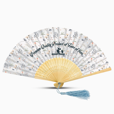 A white hand fan featuring a floral design and a blue tassel, elegantly displayed against a neutral background.