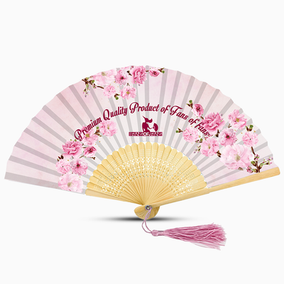 A pink hand fan featuring a floral design and a pink tassel, elegantly displayed against a neutral background.