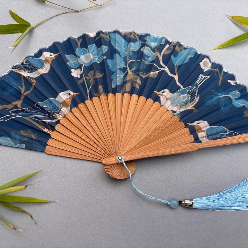 Decorative fan with floral and bird design on a gray background