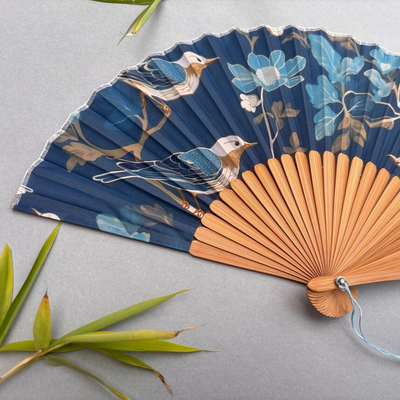 Decorative fan with floral and bird design on a gray background