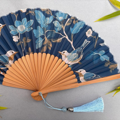 Decorative fan with floral and bird design on a gray background