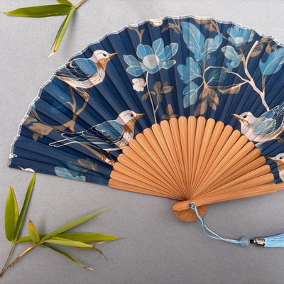 Decorative fan with floral and bird design on a gray background