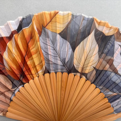 Handheld fan with leaf pattern on a gray background