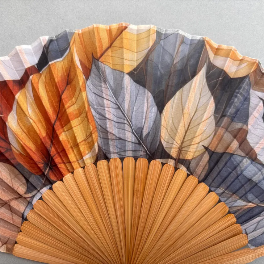 Handheld fan with leaf pattern on a gray background