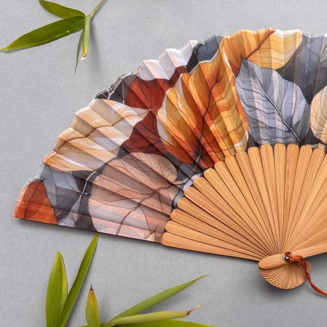 Handheld fan with leaf pattern on a gray background