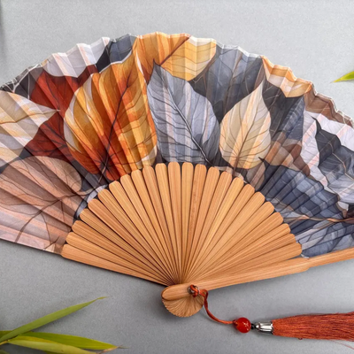 Handheld fan with leaf pattern on a gray background