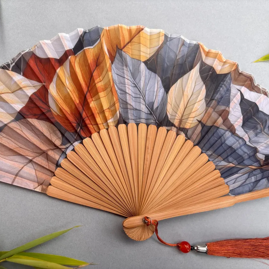 Handheld fan with leaf pattern on a gray background