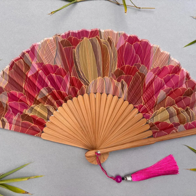 Decorative hand fan with floral design and pink tassel on a white background