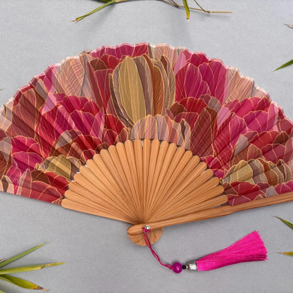 Decorative hand fan with floral design and pink tassel on a white background