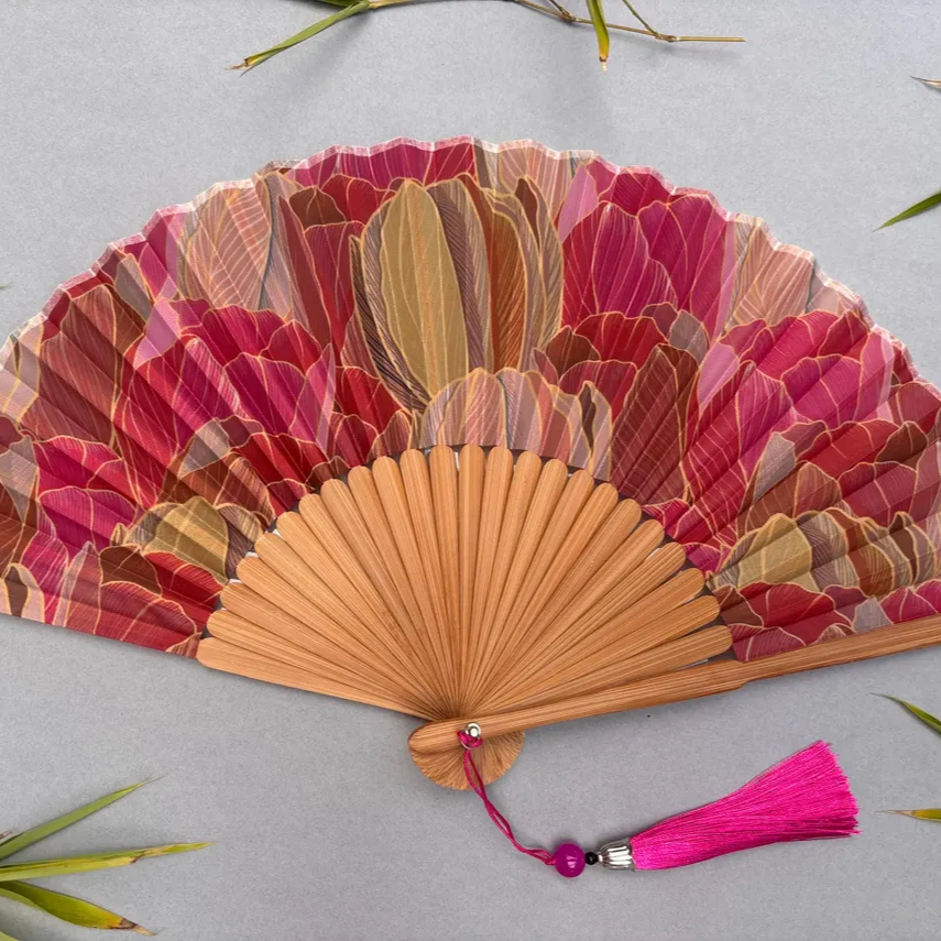 Decorative hand fan with floral design and pink tassel on a white background