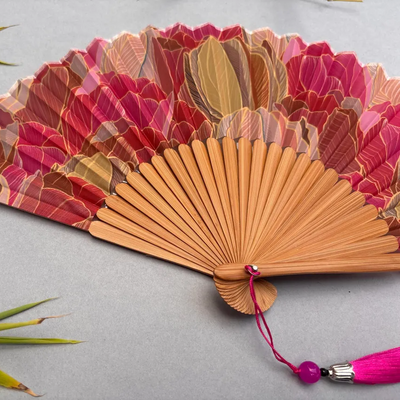 Decorative hand fan with floral design and pink tassel on a white background