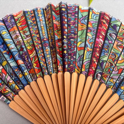 Colorful hand-fan with bamboo structure and decorative tassel on a light gray background