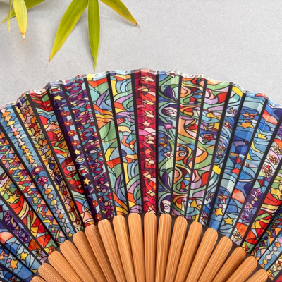 Colorful hand-fan with bamboo structure and decorative tassel on a light gray background
