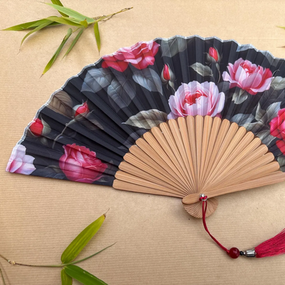 Handheld fan with floral design on a wooden surface