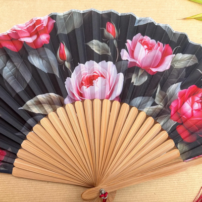 Handheld fan with floral design on a wooden surface