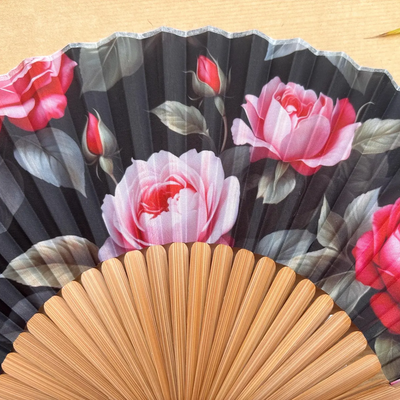 Handheld fan with floral design on a wooden surface
