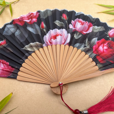 Handheld fan with floral design on a wooden surface