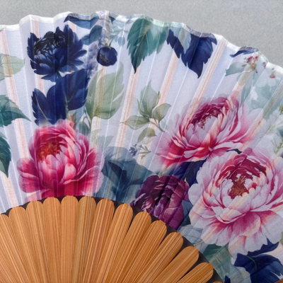 Floral-patterned hand fan on a gray background