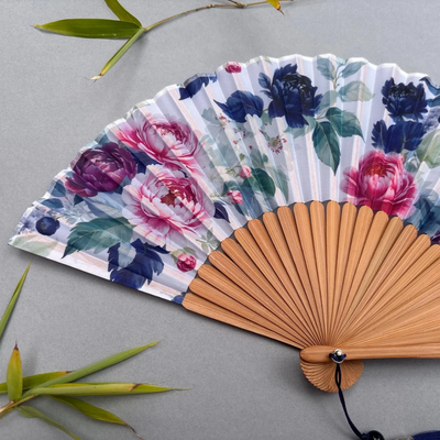 Floral-patterned hand fan on a gray background