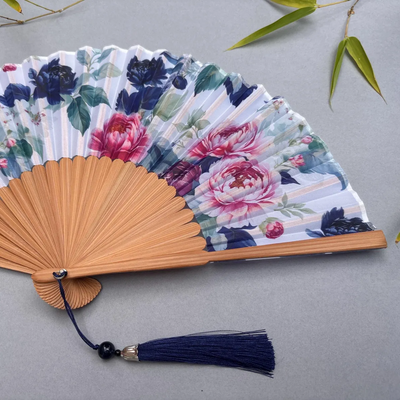 Floral-patterned hand fan on a gray background
