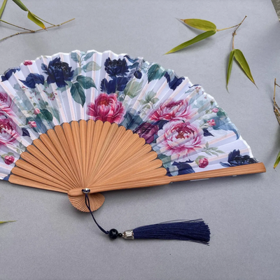 Floral-patterned hand fan on a gray background