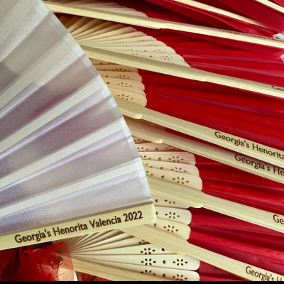 Custom engraved bamboo hand fans with red and white fabric, personalised with 'Georgia's Henorita Valencia 2022' for a special event.