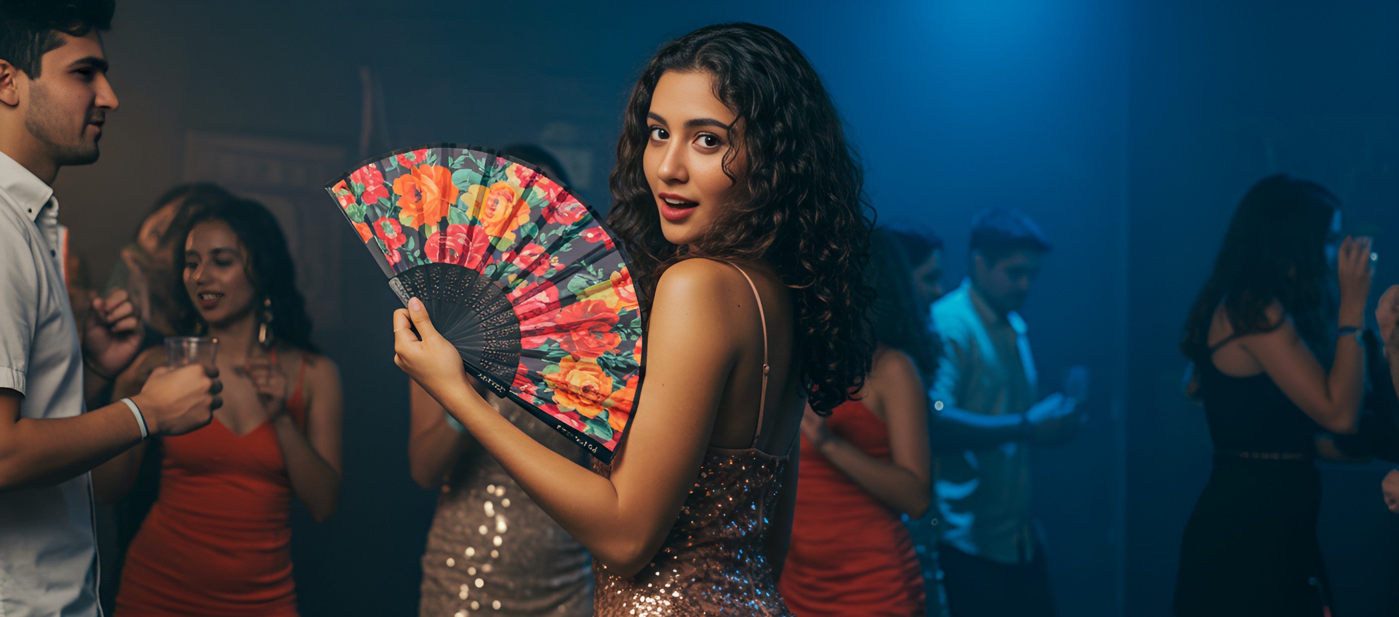 A woman elegantly holds a fabric fan while enjoying herself at a lively party.