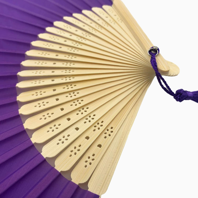 A Purple fabric fan with a tassel, showcasing a solid color design.#solid_fabric-purple
