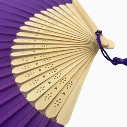 A Purple fabric fan with a tassel, showcasing a solid color design.