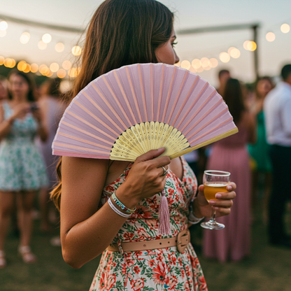 A woman at a party elegantly holds a pink hand fan, adding a touch of style to the festive atmosphere.