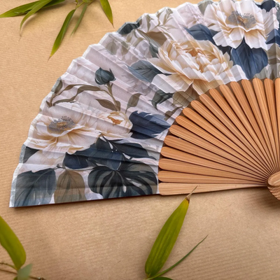 Floral-patterned hand fan with a tassel on a wooden surface