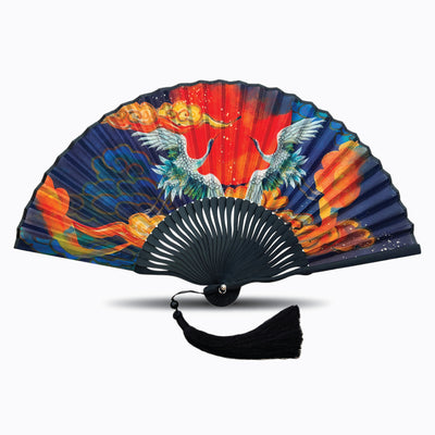Navy blue silk folding hand fan with vibrant artwork of two cranes, fiery red and orange clouds, and a black tassel, displayed open on a white background