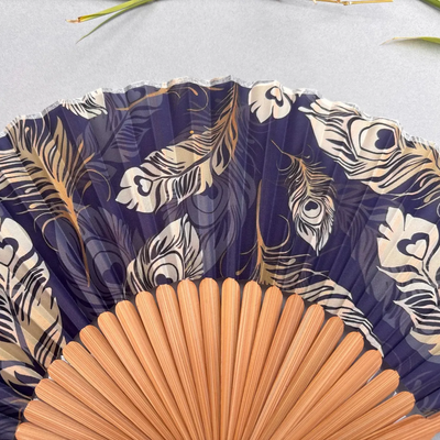 Handheld fan with peacock feather pattern on a gray background